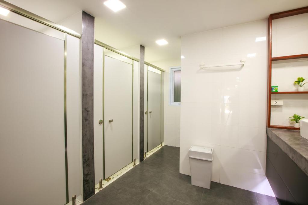 a bathroom with white walls and a shower and a toilet at Lafami Hostel in Ban Nongdouang