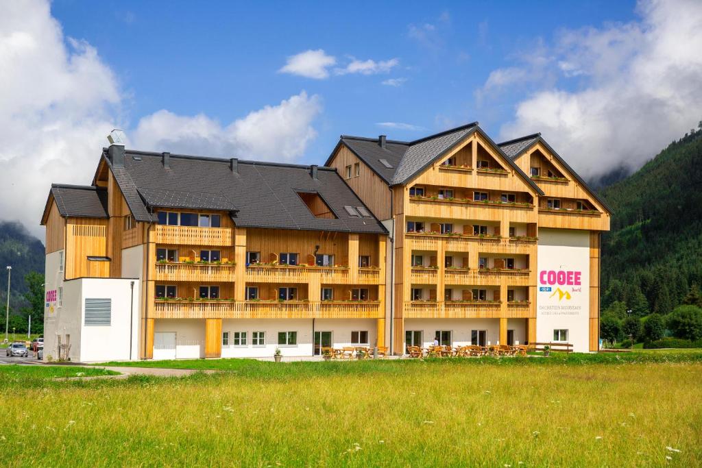 um grande edifício com um campo de relva em frente em COOEE alpin Hotel Dachstein em Gosau