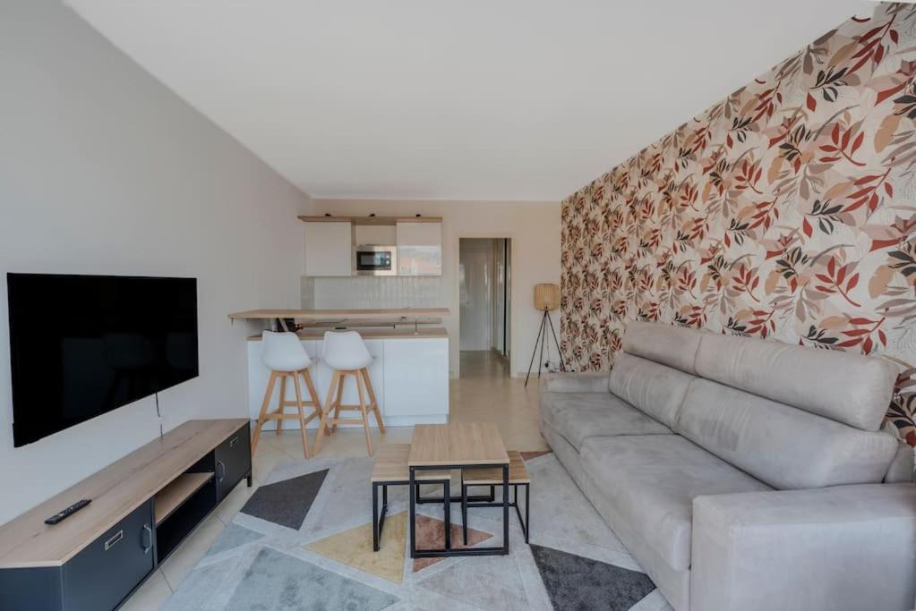 a living room with a couch and a tv at Le Grand Hôtel -Centre Croisette in Cannes