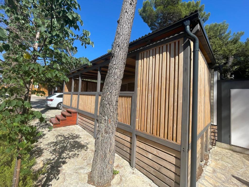 una casa con una valla de madera y un árbol en Mobile home Maris, en Biograd na Moru