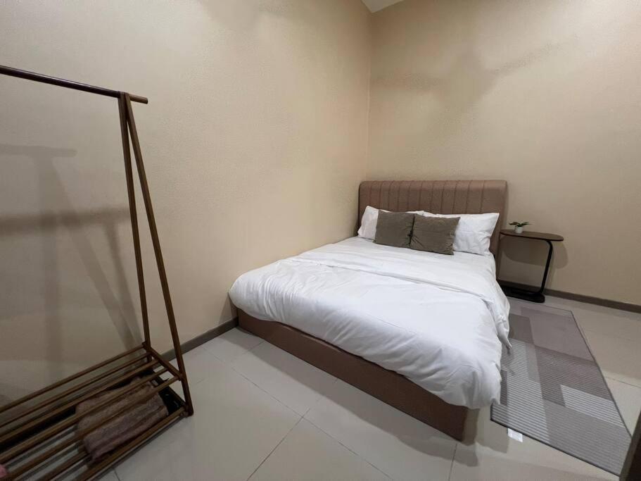 a small bedroom with a bed with white sheets at RUMAH SAUJANA KLIA by IMPIAN HOMESTAY in Sepang