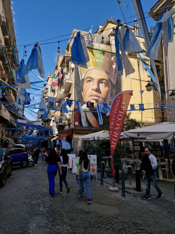 a group of people walking down a street with blue flags at Seventeen Home in Naples