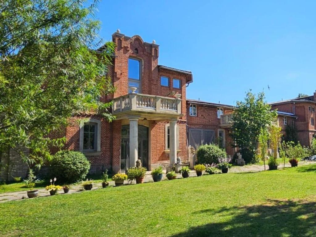 a brick house with a balcony on a lawn at Gutshofblick XL in Hanshagen
