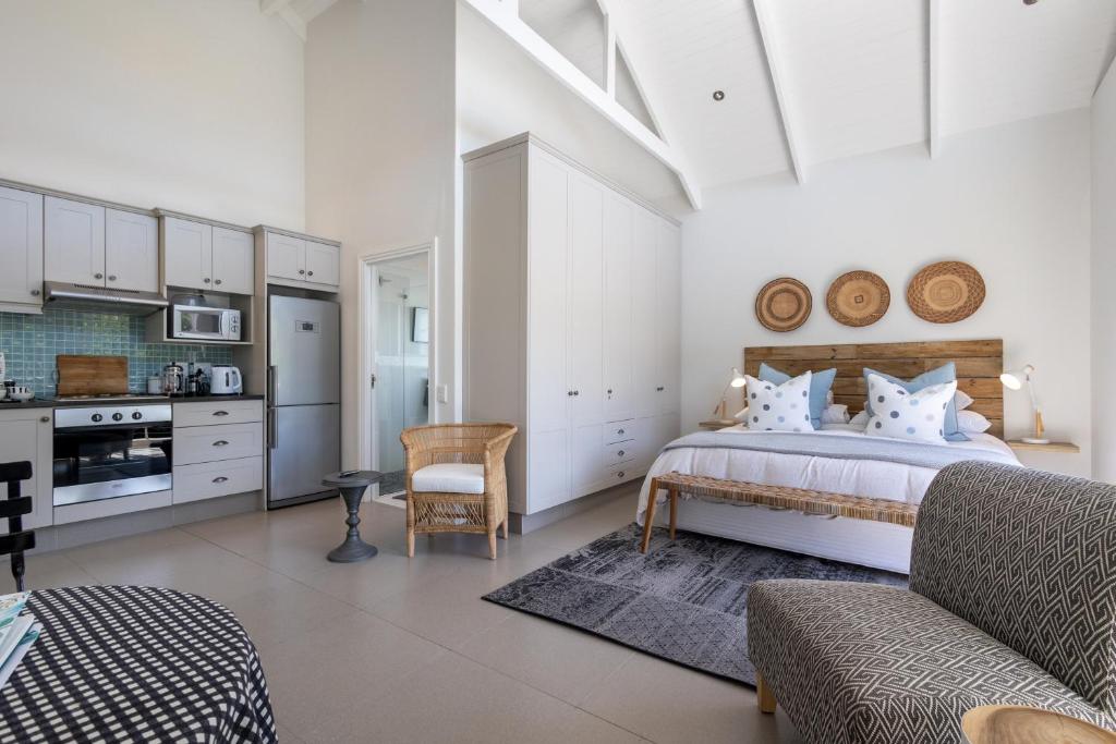 Un dormitorio blanco con una cama y una cocina. en Stableford Beachhouse Top Apartment, en Plettenberg Bay