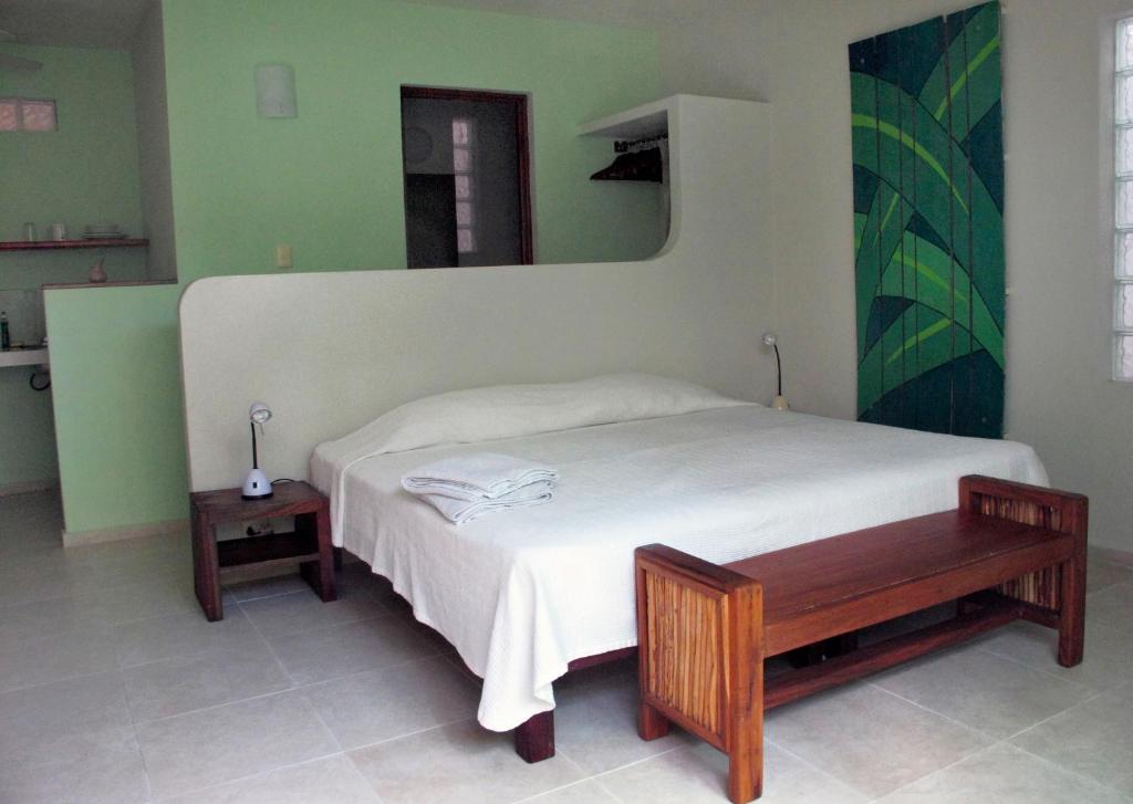 a bedroom with a bed with a bench and a mirror at Elements of the Island in Isla Mujeres
