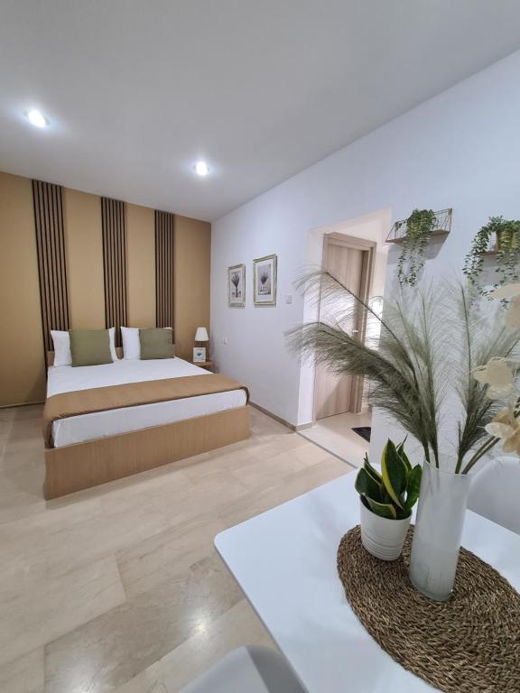 ein Schlafzimmer mit einem Bett und einem Tisch mit einer Pflanze in der Unterkunft Apartment in the heart of the city 5G in Larisa