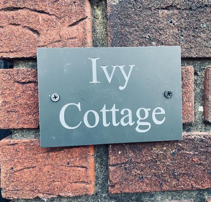 a sign on a brick wall with the words ivy cottage at Ivy Cottage Two Bedroom & Garden in Temple Fortune in London