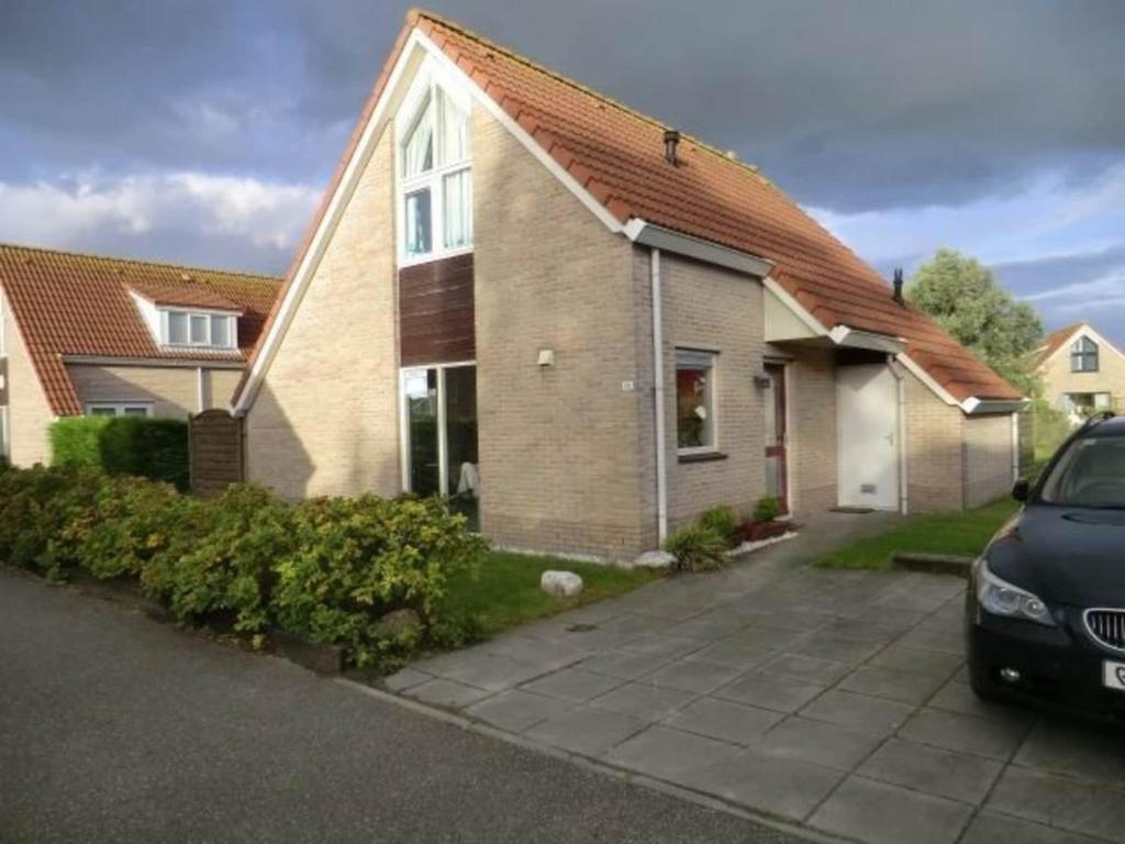 a house with a car parked in front of it at Bungalow in Breskens near the Beach in Breskens