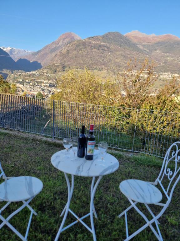 un tavolo con due bottiglie di vino e due sedie di Appartamento Panorama Valtellina Relax Garden a Sondrio
