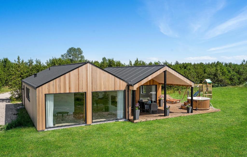 a large wooden house with glass doors on a field at 3 Bedroom Stunning Home In Jerup in Jerup
