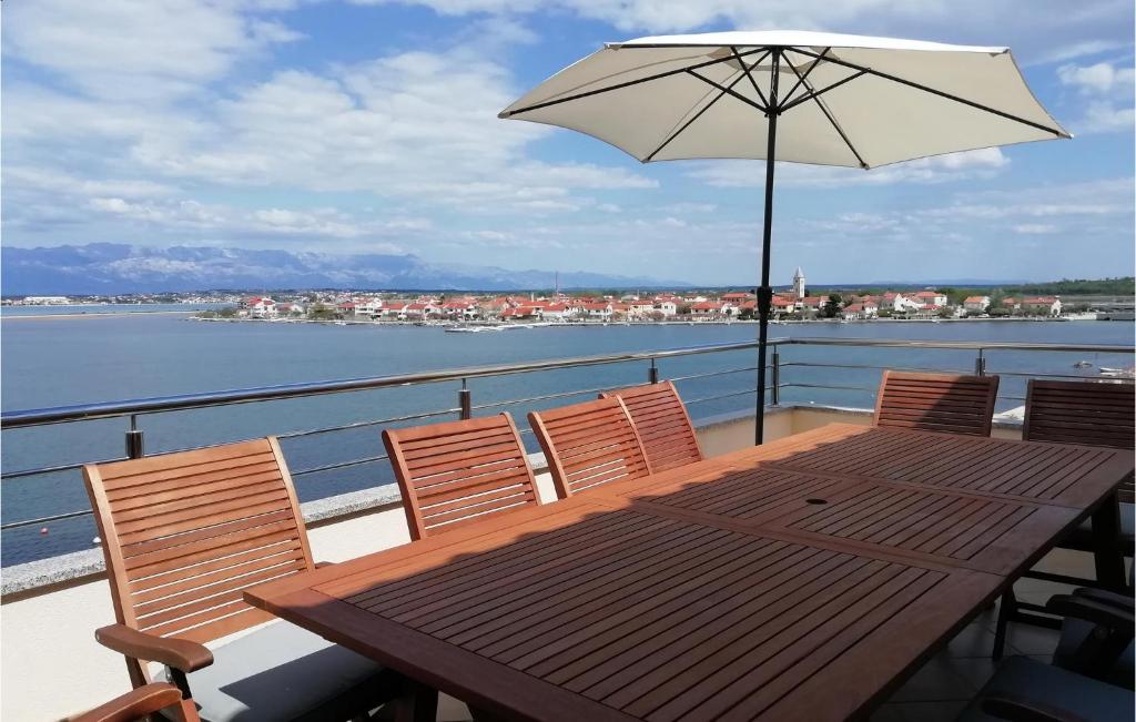 drewniany stół i krzesła z parasolem na balkonie w obiekcie 6 Bedroom Cozy Apartment In Nin w Nin
