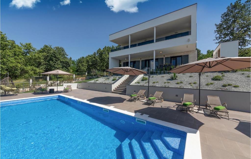 a swimming pool with chairs and umbrellas in front of a house at Villa Althea in Ružići