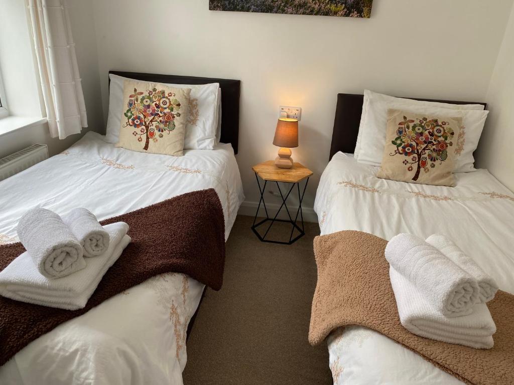 twee bedden met handdoeken in een slaapkamer bij Simla Bungalow, Tetney in Tetney