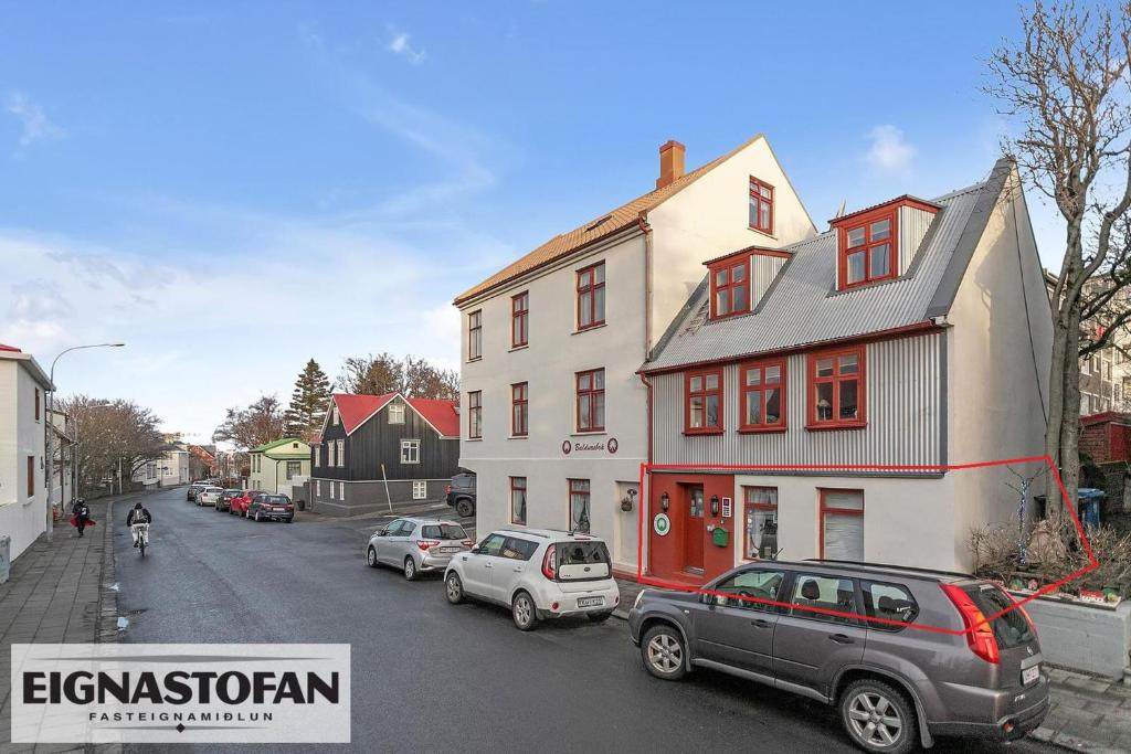 a street with cars parked in front of a house at Downtown Reykjavik Studio Apartment in Reykjavík