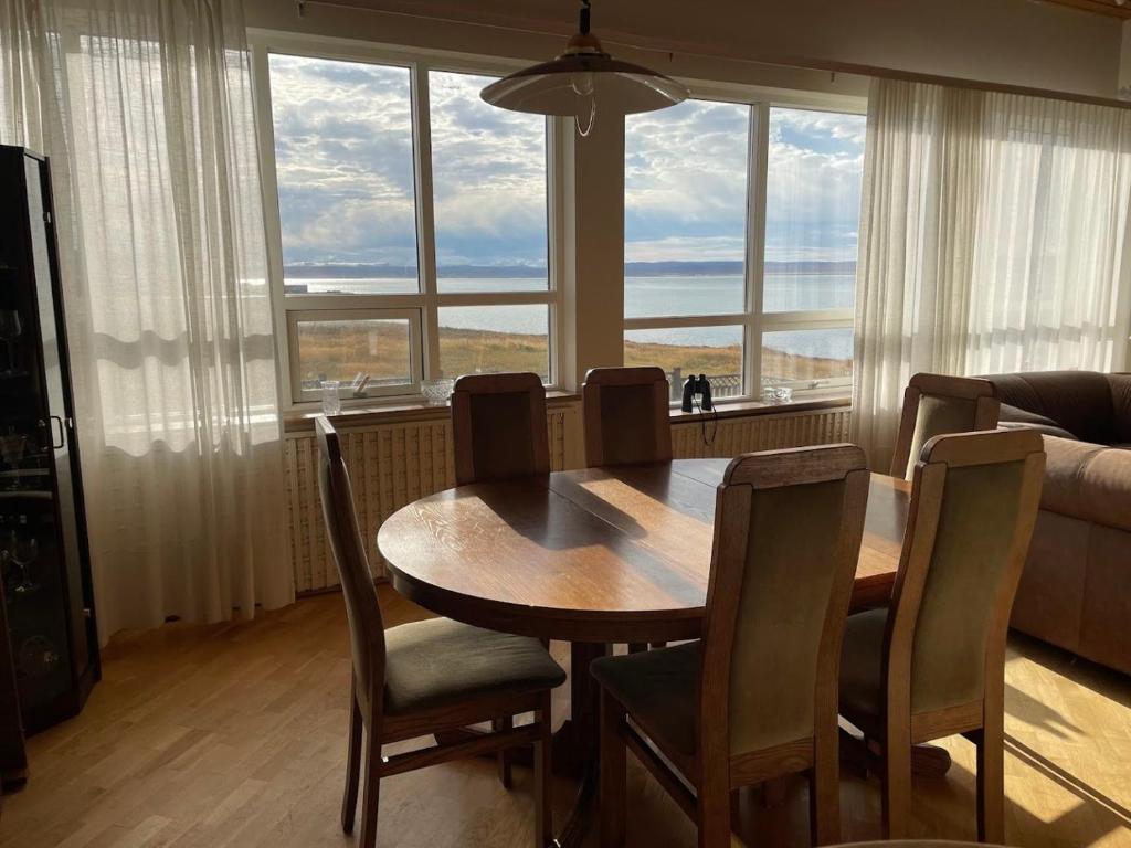 a dining room with a table and chairs in front of a window at Ingimarsstaðir in Þórshöfn