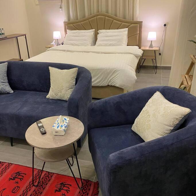 a bedroom with a bed and two blue couches at شقة أنيقة وصغيرة للعائلات من غرفتين نوم - وصول ذاتي in Taif