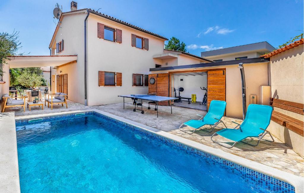 a pool with two chairs and a table next to a house at 4 Bedroom Cozy Home In Barbariga in Barbariga