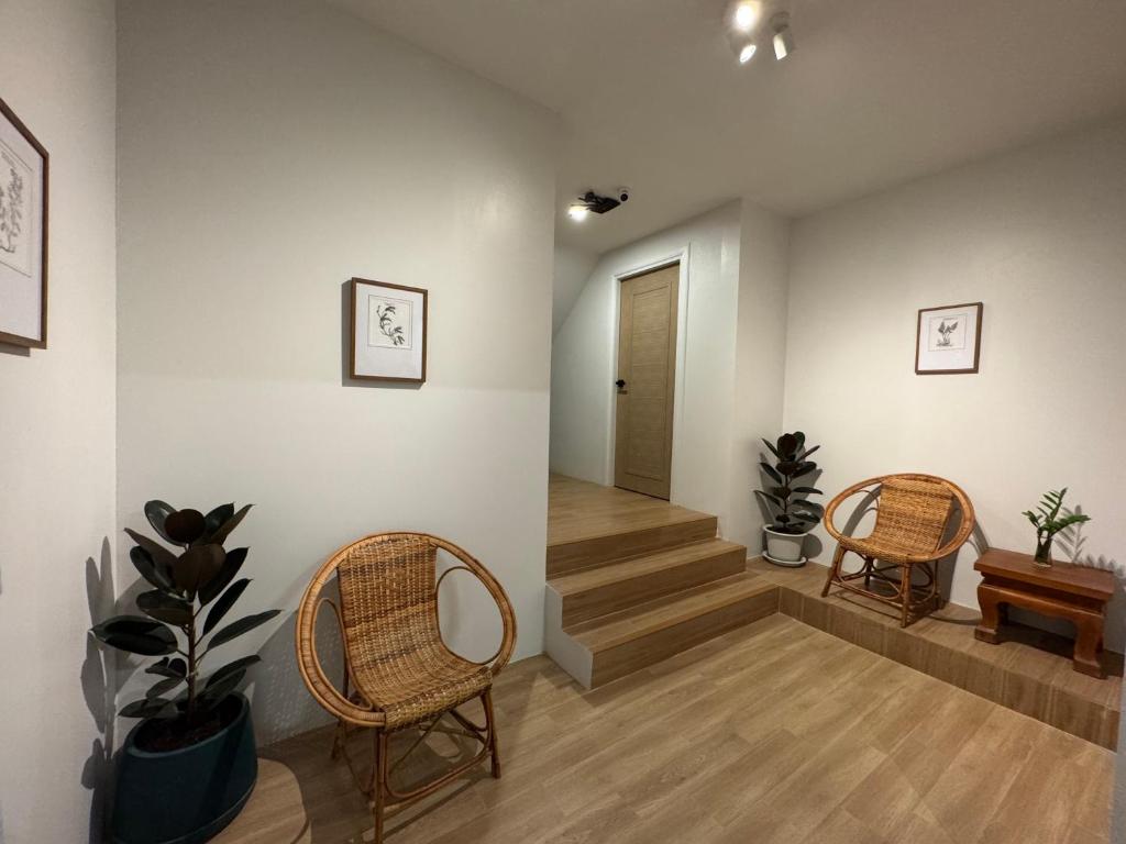 A small, warmly lit landing with wicker chairs beside a stairway and interior door.