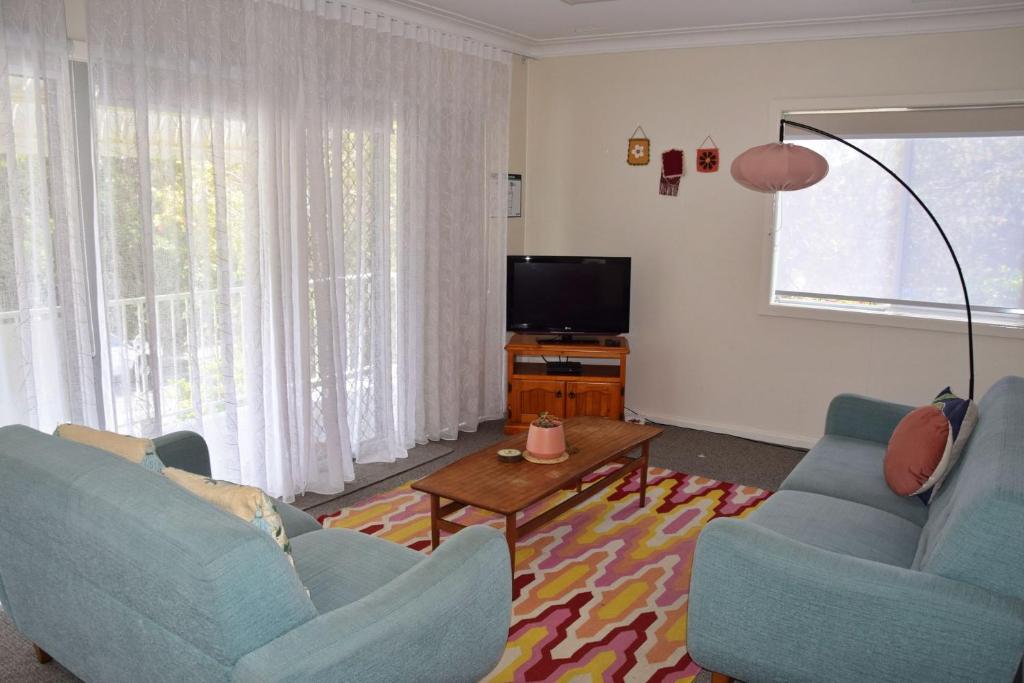 a living room with two blue chairs and a television at Mariner 16 Flat 2 - Bring your own linen. in South West Rocks