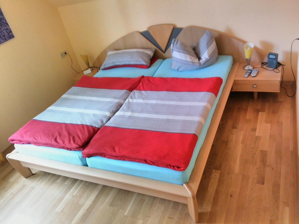 ein Bett mit roten und weißen Decken und einem Nachttisch in der Unterkunft Oberhof Apartment in Oberhof