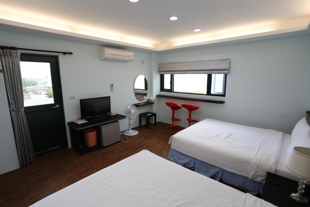 a bedroom with two beds and a desk with a television at See Your Dreams B&amp;B in Magong