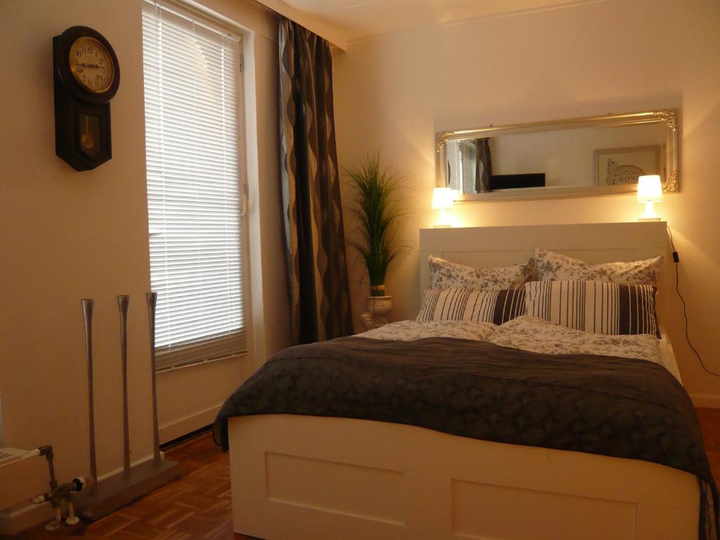 1 dormitorio con cama, reloj y ventana en Pension Louisa en Dagebüll