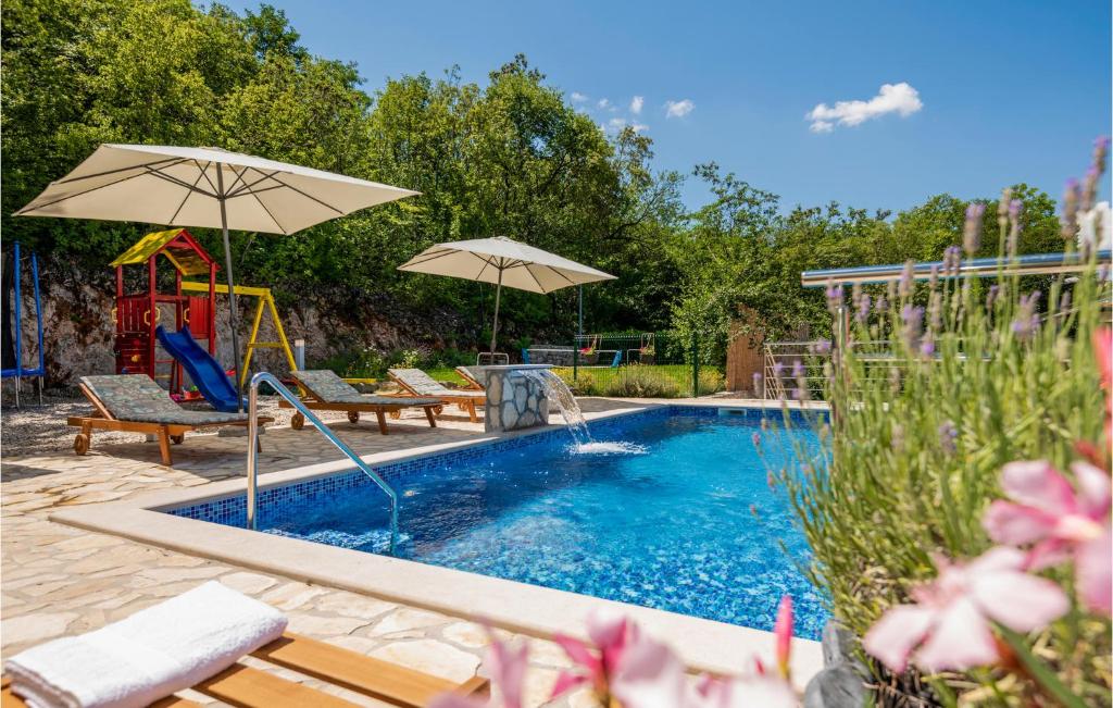 basen ze zjeżdżalnią i plac zabaw z parasolami w obiekcie Four-Bedroom Holiday Home In Grubine w mieście Grubine