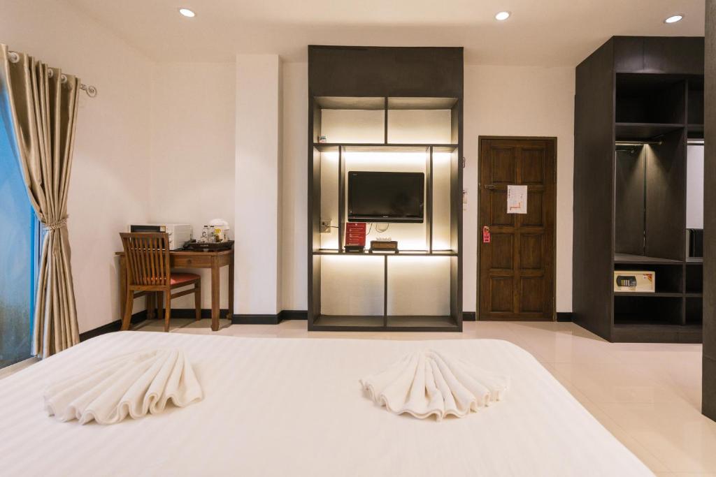 A spacious-looking bedroom with a desk, TV unit and open wardrobe.