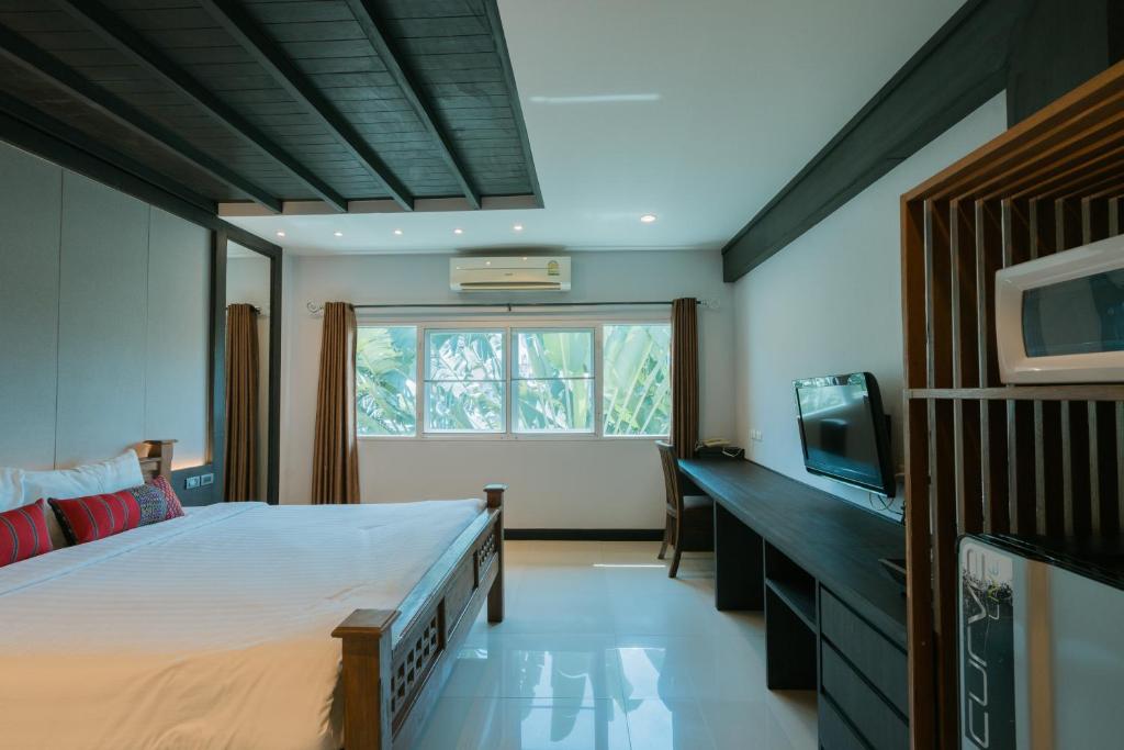 A bright bedroom with a wooden bed, television, desk and garden-facing window.