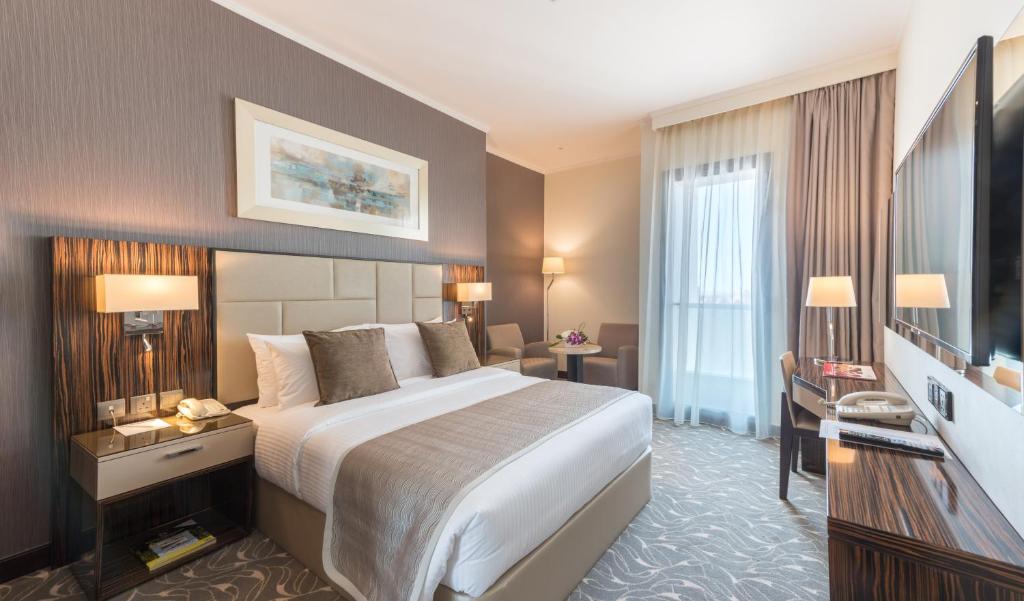 um quarto de hotel com uma cama grande e uma secretária em Hawthorn Extended Stay by Wyndham Abu Dhabi City Center em Abu Dhabi