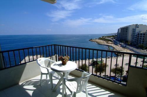 een balkon met een tafel en stoelen en de oceaan bij Roma Hotel in Sliema