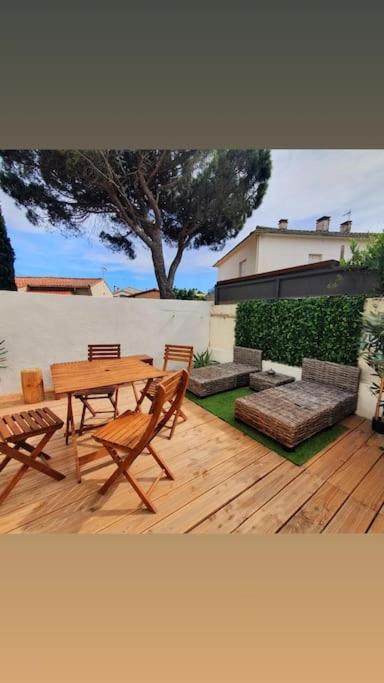une terrasse en bois avec une table, des chaises et un arbre dans l'établissement 2 terrasses JolieT2 clim, parking privé, à Canet