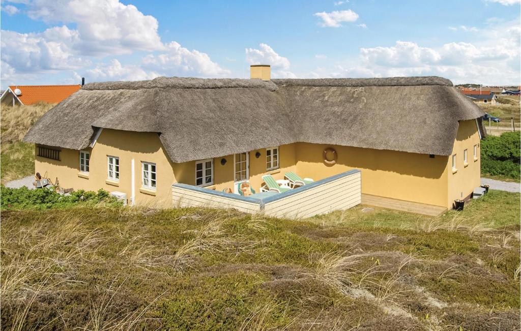 a house with a thatched roof on top of a field at Holiday Home Rauhesvej Hvide Sande in Bjerregård