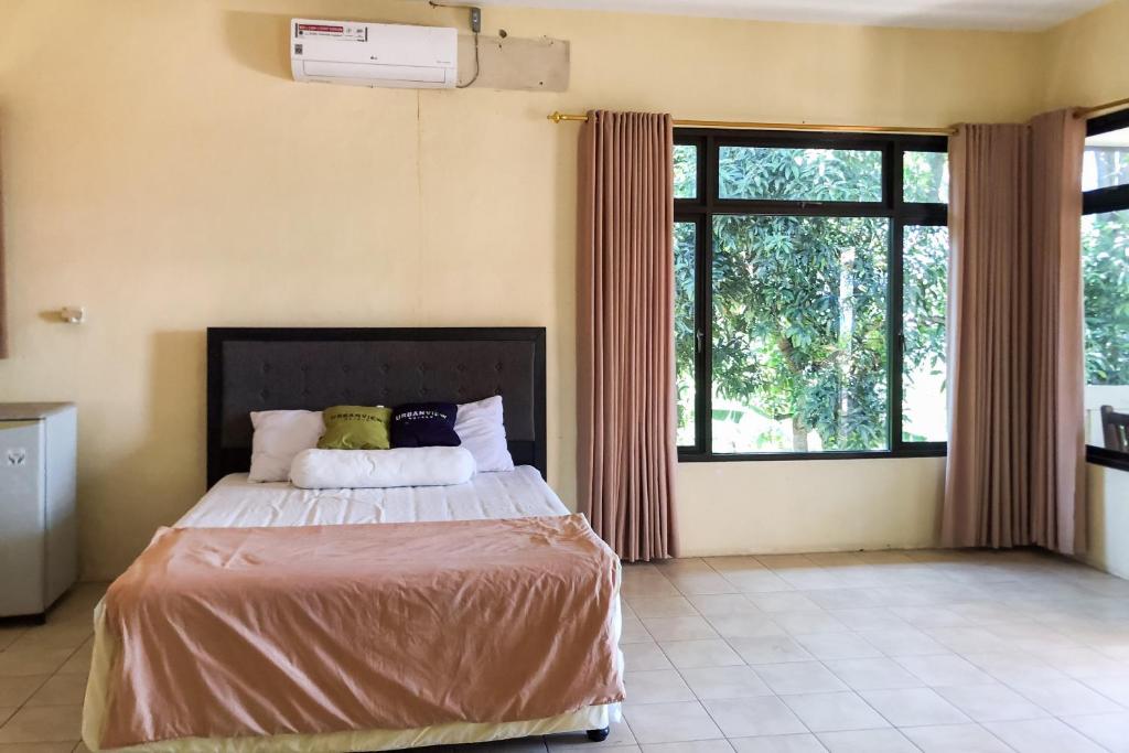 a bedroom with a bed and a large window at Urbanview Umbul Tanjung Resort Anyer in Sukanegara
