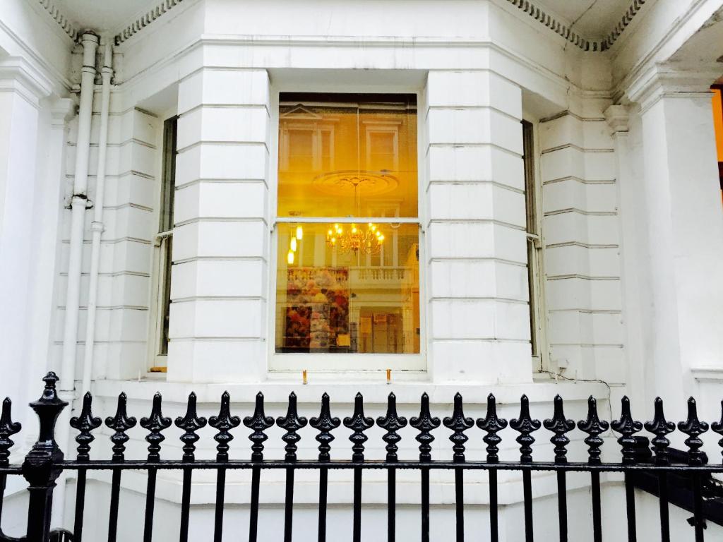ロンドンにあるAcacia Hotelの窓付きの建物前の黒い柵