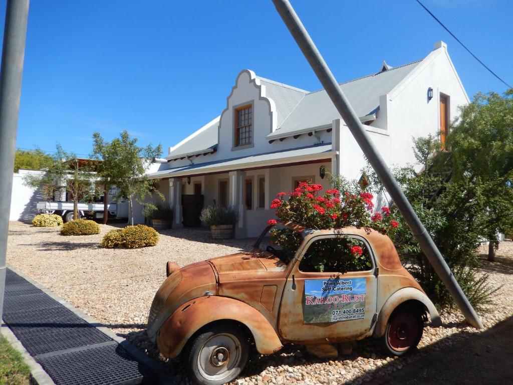 an old truck with flowers on the back in front of a house at Karoo-Rust in Prince Albert