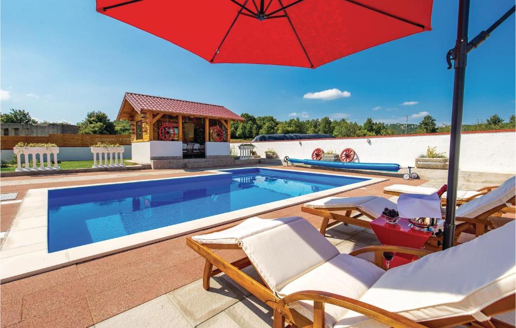 piscina con sedie e ombrellone accanto a piscina di Cozy Home In Gospic With Sauna a Gospić