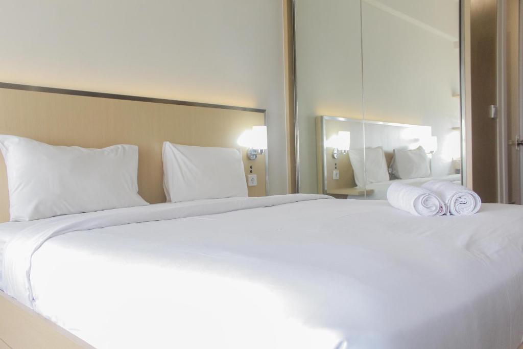 a bedroom with a large white bed with towels on it at Comfort Minimalist Studio at Parkland Avenue Apartment By Travelio in Tangerang
