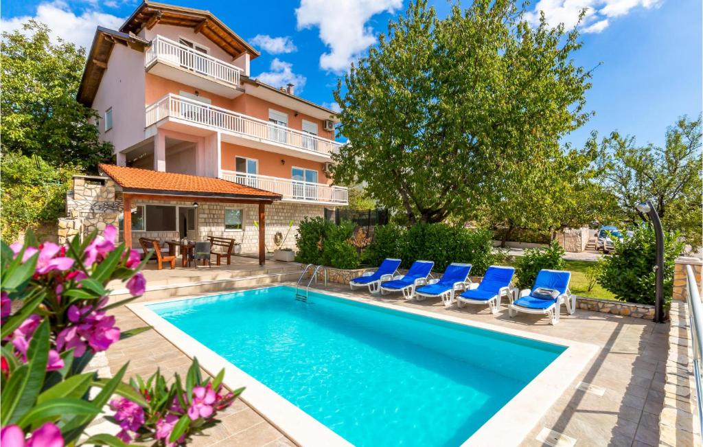 a swimming pool in front of a house with blue chairs at Holiday Home Imotski 04 in Imotski