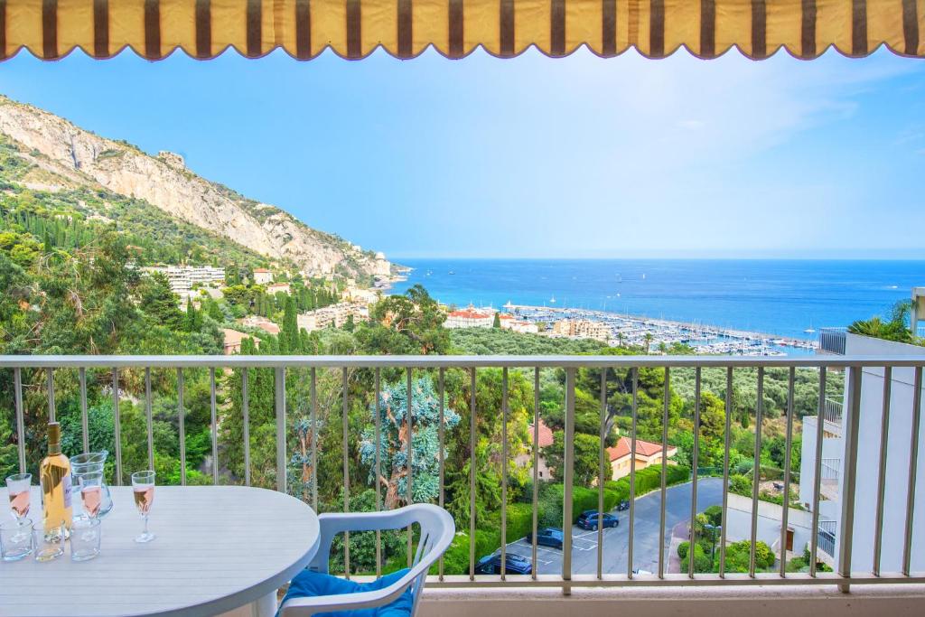 un balcon avec une table et des chaises et l'océan dans l'établissement Le Mirador, vue mer, piscine, terrasse, à Menton