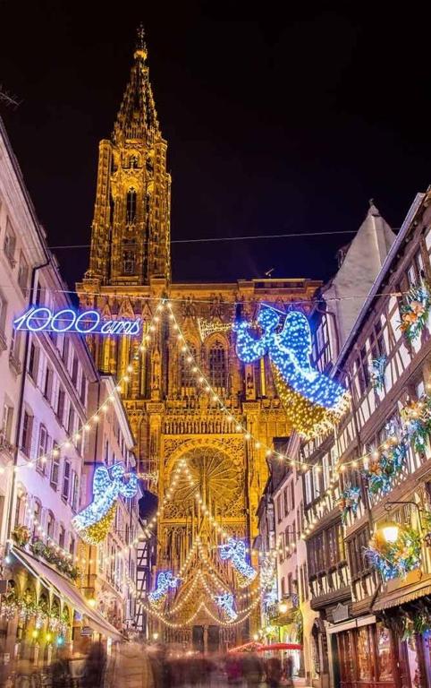 un grand bâtiment avec des lumières de Noël en face dans l'établissement Maison neuve chaleureuse pour 1 à 4 personnes, à Schiltigheim