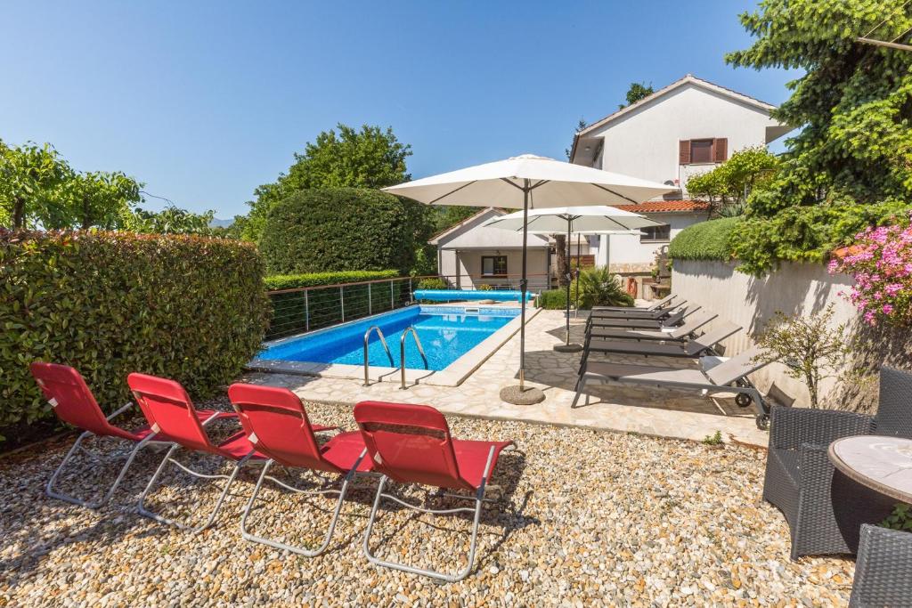 a group of red chairs and a swimming pool at Apartments Dorijan with Pool in Matulji