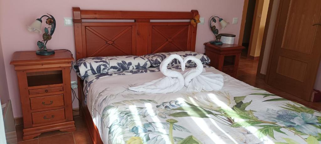 two white swans are sitting on a bed at La belleza del Tietar in Lanzahita