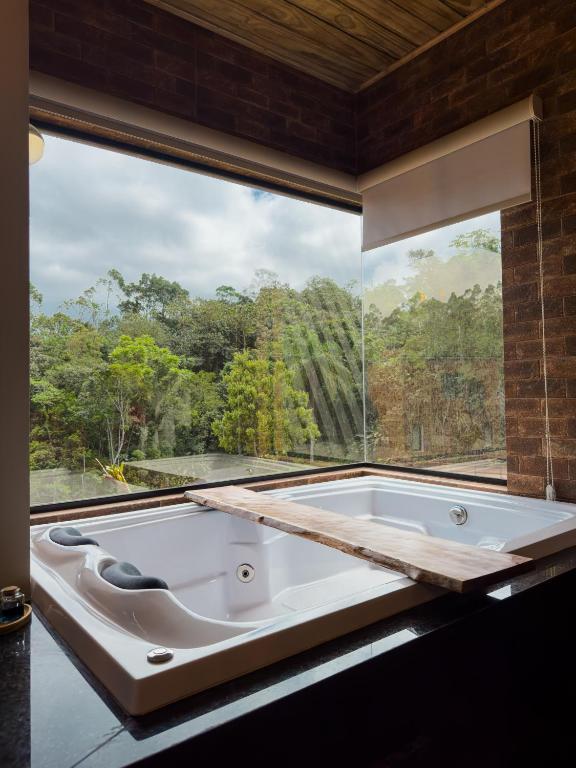 a bath tub in a room with a large window at Pousada Duas Marias in Nova Veneza