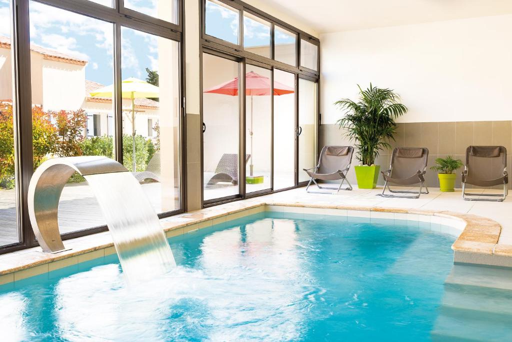 una piscina con una fuente de agua en una casa en Lagrange Vacances L’Oustau de Sorgue, en LʼIsle-sur-la-Sorgue