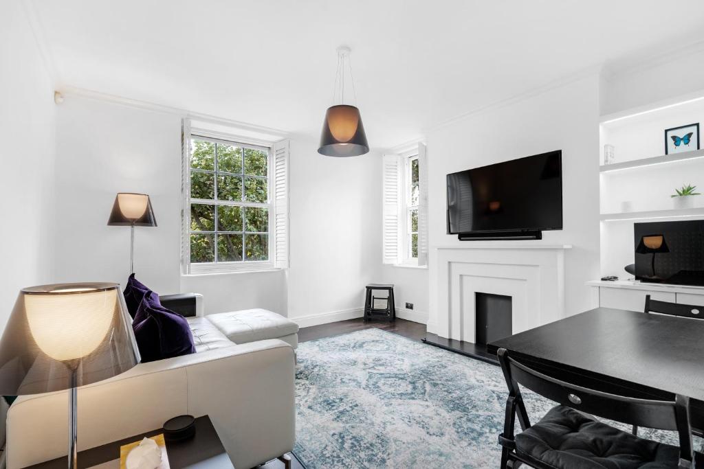 a white living room with a couch and a tv at The Bronwen in London