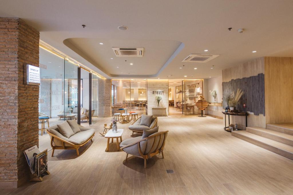 a lobby with couches and chairs in a building at Clef Hotel Bangkok in Bangna