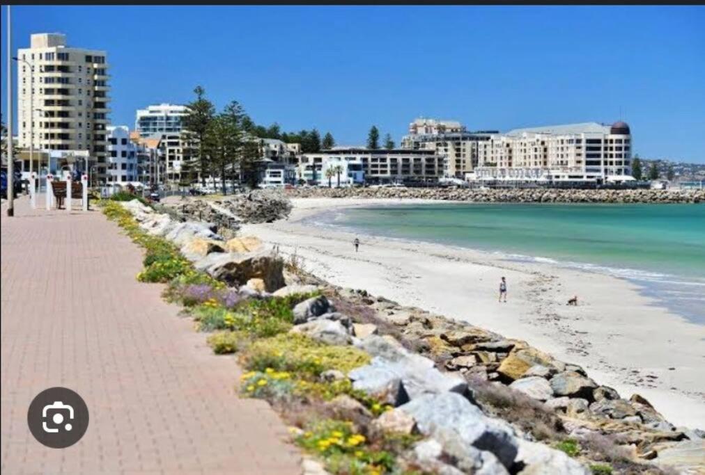 a sandy beach with buildings and the ocean at Golden sunset in Glenelg