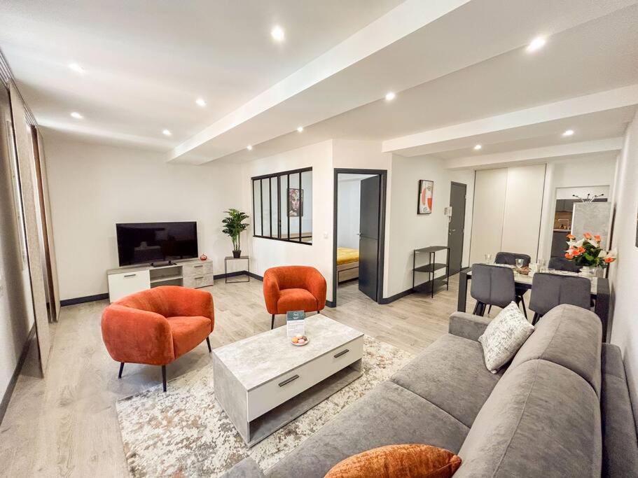 - un salon avec un canapé gris et des fauteuils orange dans l'établissement T2 refait à neuf en plein centre-ville de Sanary, à Sanary-sur-Mer