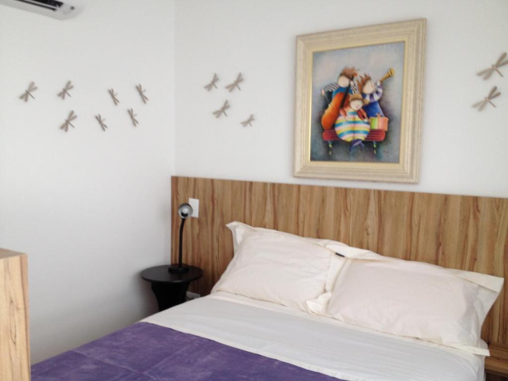 a bedroom with a bed with a painting and birds on the wall at Estúdio Vila Madalena in Sao Paulo